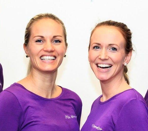 To kvinner smiler i lilla t-skjorter, står sammen foran en hvit bakgrunn.