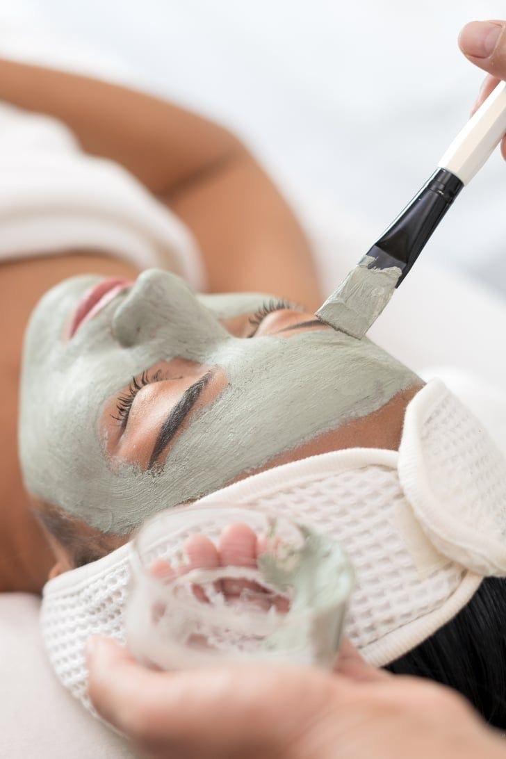 En person får ansiktsmaske påført med pensel under en spa-behandling.