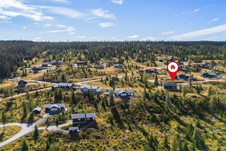 Oversiktsbilde av et hytteområde med flere hytter og skogkledde åser i bakgrunnen.