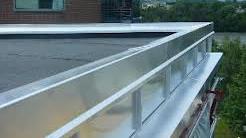 Takrenne i aluminium på en flat takoverflate, med grønt landskap i bakgrunnen.