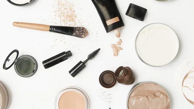 Sminkeprodukter som foundation, pudder, øyenskygge og mascara på en hvit bakgrunn.