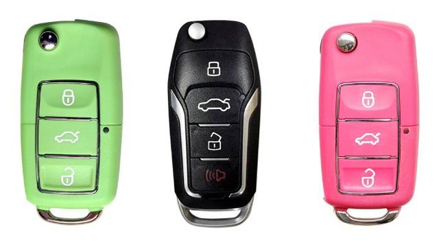 Tre bilnøkler i forskjellige farger: grønn, svart og rosa, med knapper for låsing og åpning av bilen.