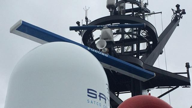 Satelitter og antenner på en skipmast med grå himmel i bakgrunnen.