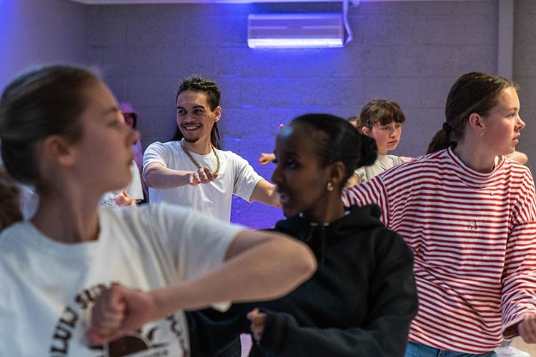 Ungdommer som danser i en moderne dansestudio med fokus på bevegelse og samarbeid.