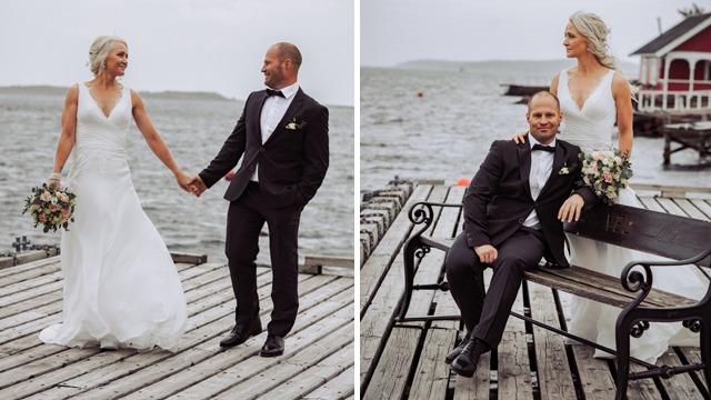 Brudeparet står på en brygge ved sjøen, iført elegant bryllupsantrekk, med blomster i hånden og en romantisk stemning.