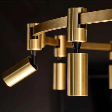 Moderne taklampe i børstet messing med justerbare lysarmaturer. Elegant design for stilig belysning.