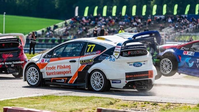 Racerbil i aksjon under et rallyløp, med flere biler i bakgrunnen og publikum på tribunen.