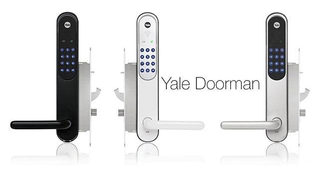 Tre Yale Doorman-låser i svart og hvitt med tastatur og håndtak, montert på en vegg.