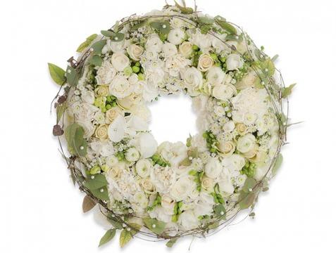 En vakker blomsterkrans laget av hvite roser, små blomster og grønne blader, perfekt for dekorasjon.