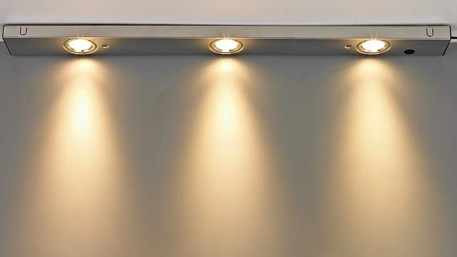 Tre moderne taklamper med varmt lys som lyser opp en vegg.