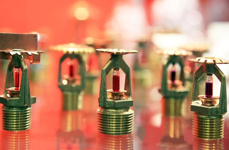 Sprinklerhoder med røde glassrør, plassert på en reflekterende overflate.