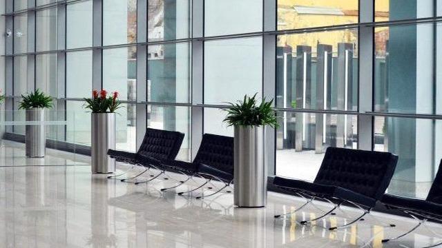 Moderne lobby med glassvegger, stilige stoler og grønne planter i sølvfargede potter.