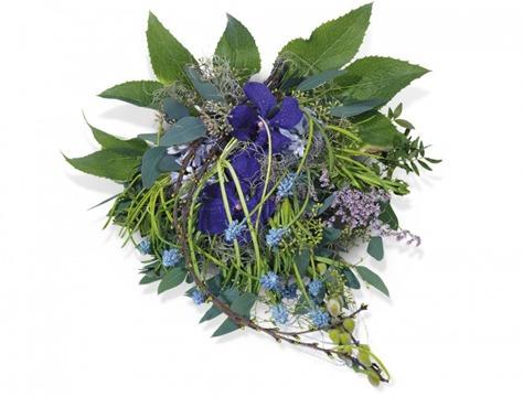 En fargerik bukett med lilla fioler, blå blomster og grønne blader, dekorert med urter og små kvister.