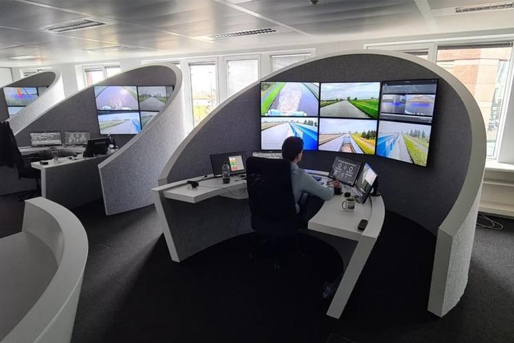 En operatør sitter ved et moderne kontrollrom med flere skjermer som viser overvåkningsbilder av veier.