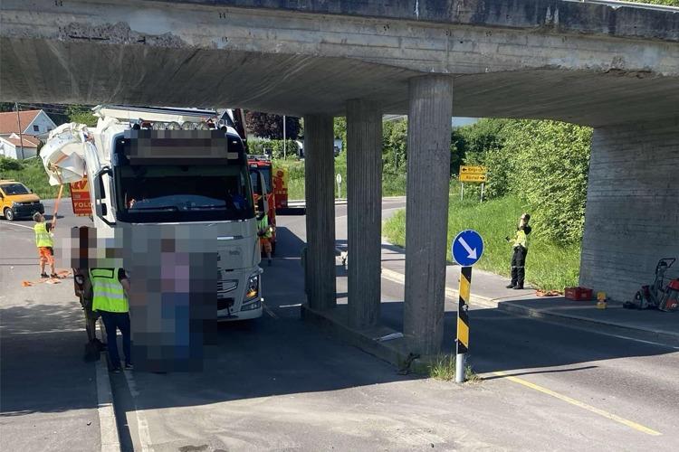 En lastebil står under en bro, med redningsmannskap som jobber på stedet. Veien er avstengt for trafikk.