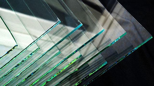 Lag med klart glass stablet oppå hverandre, med skarpe kanter og reflekterende overflater.