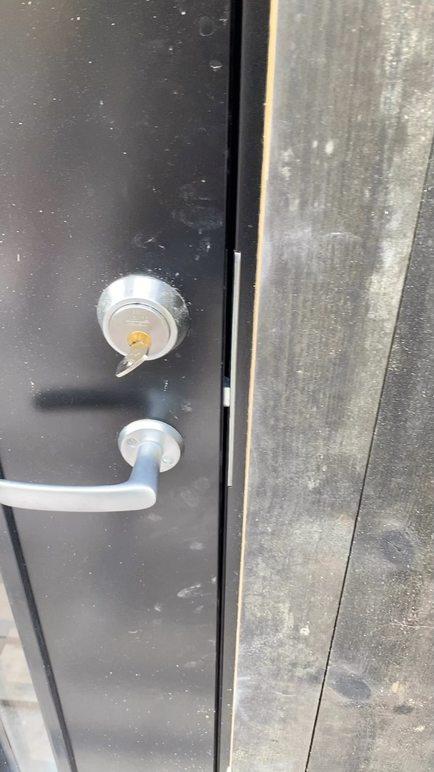 Nærbilde av en svart dør med en lås og dørhåndtak i metall.