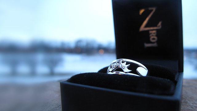 En sølvring med en stjerneformet diamant, plassert i en svart smykkeske.