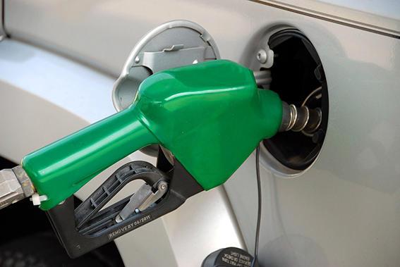 Grønn bensinpumpe som fyller drivstoff i en biltank.