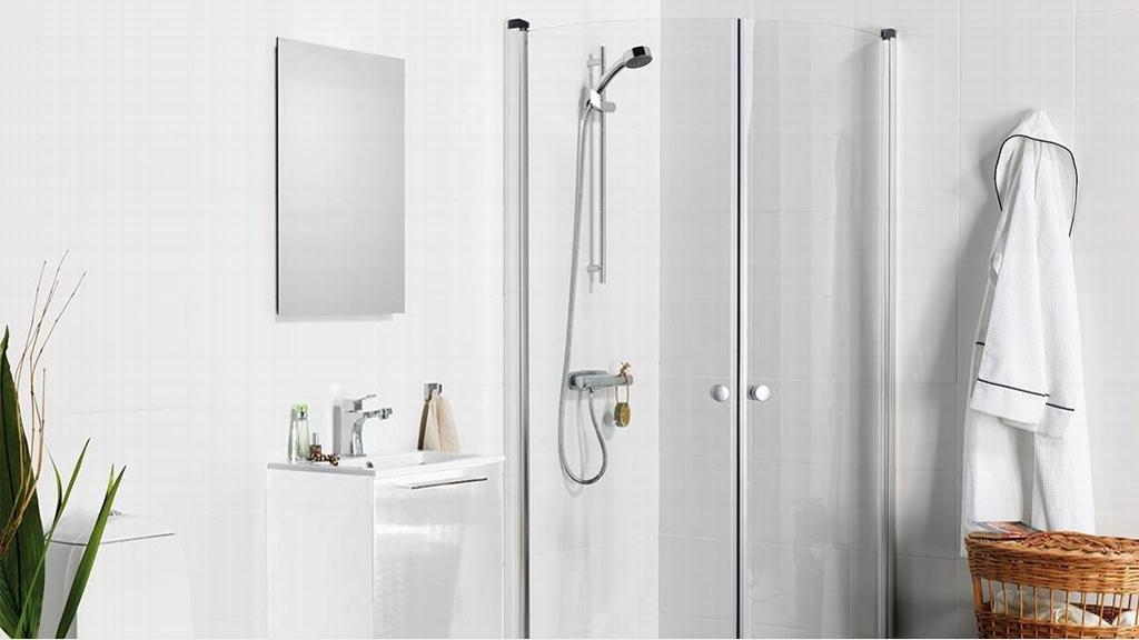 Moderne baderom med dusj, speil, servant, håndkle og en kurv i et lyst og stilrent design.