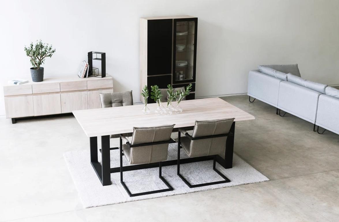 Moderne stue med et lyst spisebord, stoler, en sofa og en hylle i minimalistisk design.