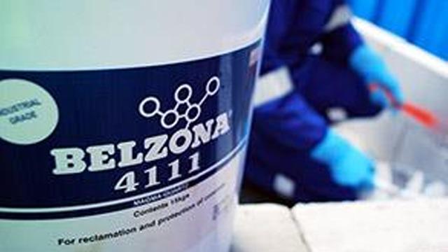 En bøtte med Belzona 4111, et produkt for rehabilitering og beskyttelse, med en person i bakgrunnen som arbeider.