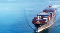 Et stort containerskip seiler gjennom det blå havet med last av fargerike containere.