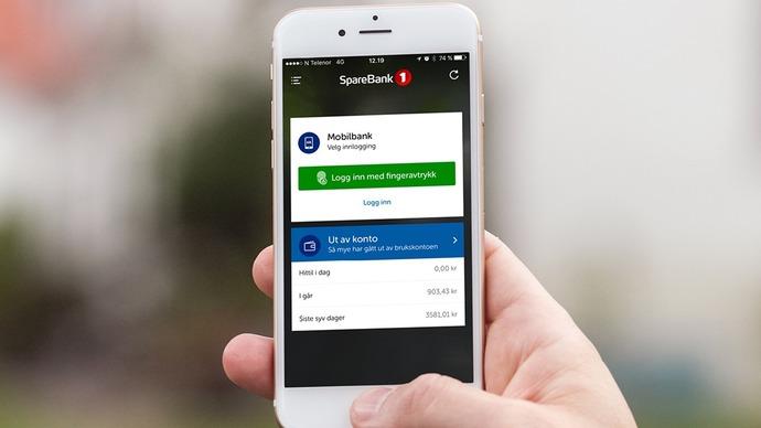 En person holder en smarttelefon som viser en mobilbankapp med saldo og transaksjonsdetaljer.