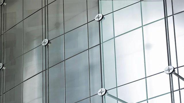 Moderne glassfasade med metallbeslag og reflekterende overflater på en bygning.