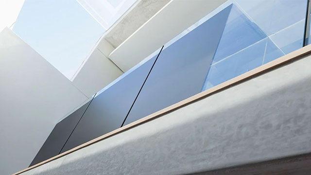 Moderne balkong med glassrekkverk og minimalistisk design, sett fra bakkenivå.