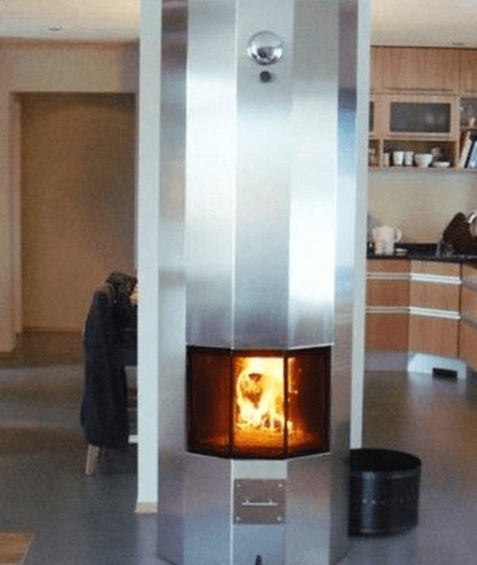 Moderne peis i stue med flammer som brenner, omringet av stål og treinteriør.