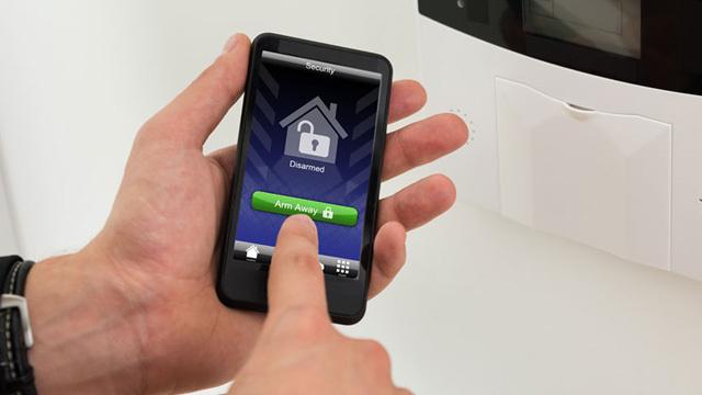 En hånd som bruker en smarttelefon til å låse opp en smart enhet med en app.