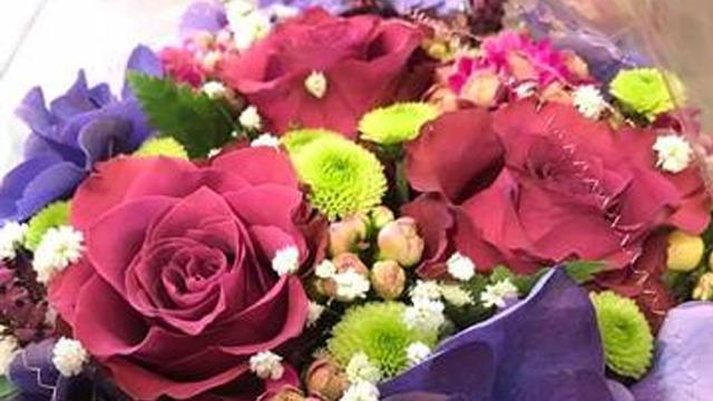 En fargerik bukett med rosa roser, lilla blomster og grønne detaljer, perfekt for en spesiell anledning.
