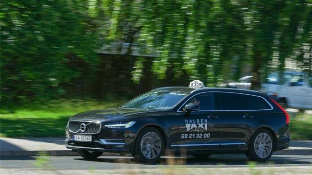 En svart Volvo taxi kjører raskt langs veien med taklys og registreringsnummer.