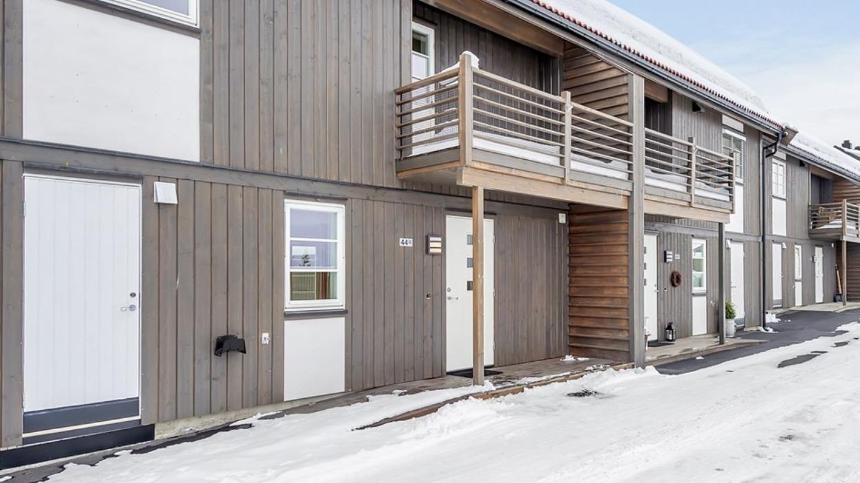 Moderne trehus med balkonger og snødekt fortau i en rolig gate.