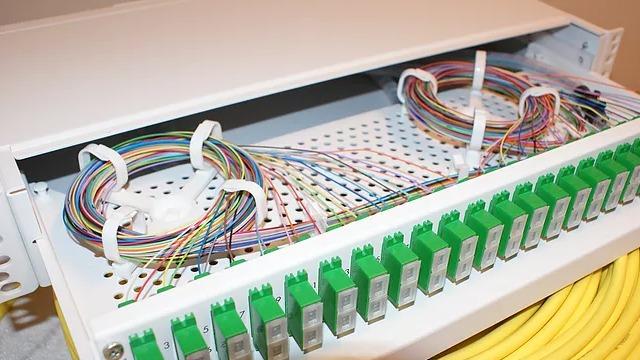 Bilde av en åpen fiberoptisk distribusjonsboks med fargede kabler og tilkoblinger.