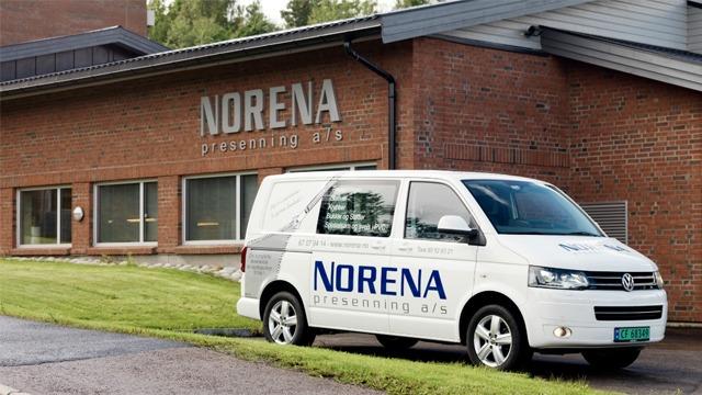 En hvit varebil med "NORENA" på siden står foran en mursteinsbygning med samme navn.