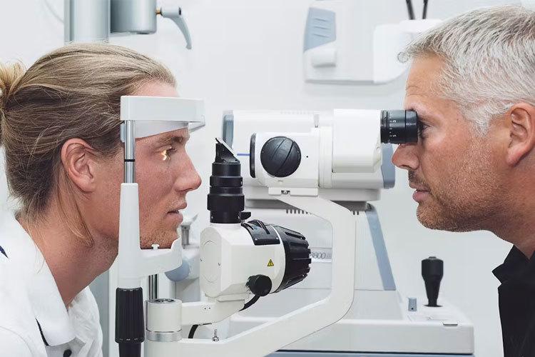 To øyne som undersøkes av en optiker med en spesiell maskin i et moderne synsrom.