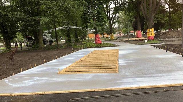 Betongplaten som legges i parken, med rammer for fremtidige konstruksjoner og trær i bakgrunnen.