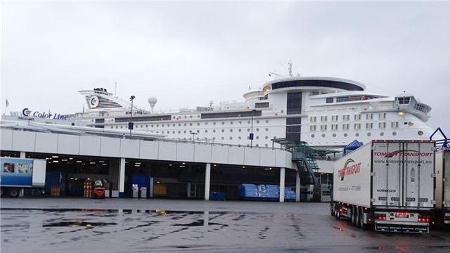Kryssningskipet "Norwegian Jewel" ligger ved kaien, med grå himmel og lastebil i forgrunnen.