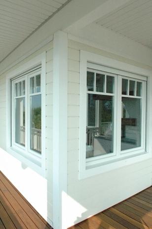 Moderne hjørnevinduer i hvit farge på en terrasse med tredekk.