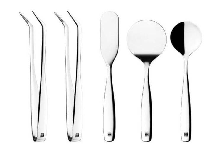 Sølvbestikk med tang, serveringsskje, og spatler i moderne design.
