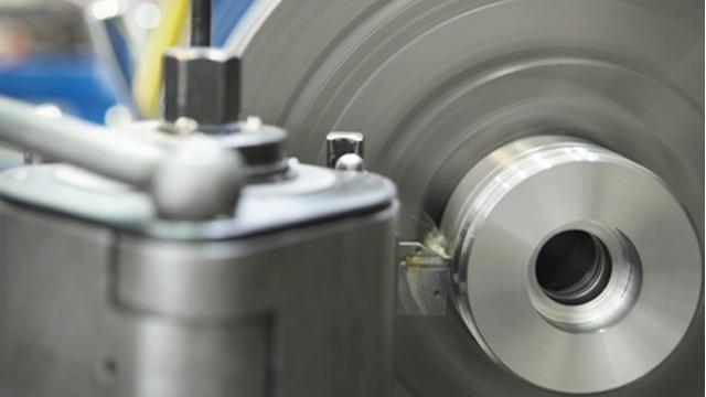 Nærbilde av en roterende maskindel med metalloverflate og presisjonsverktøy i bakgrunnen.