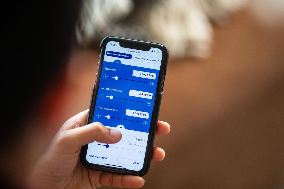 En person som holder en smarttelefon med en app som viser justeringsskjemaer for innstillinger.