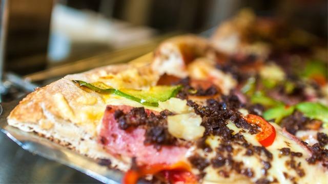 En nærbilde av en pizza med kjøttdeig, paprika, løk og ost på en metallplate.
