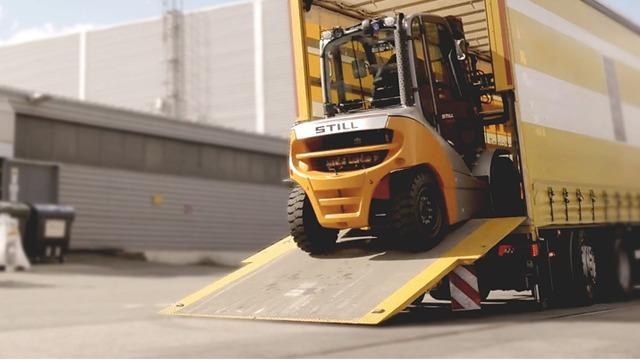 Gaffeltruck som kjører ned fra en lastebilrampe på en lagerplass.