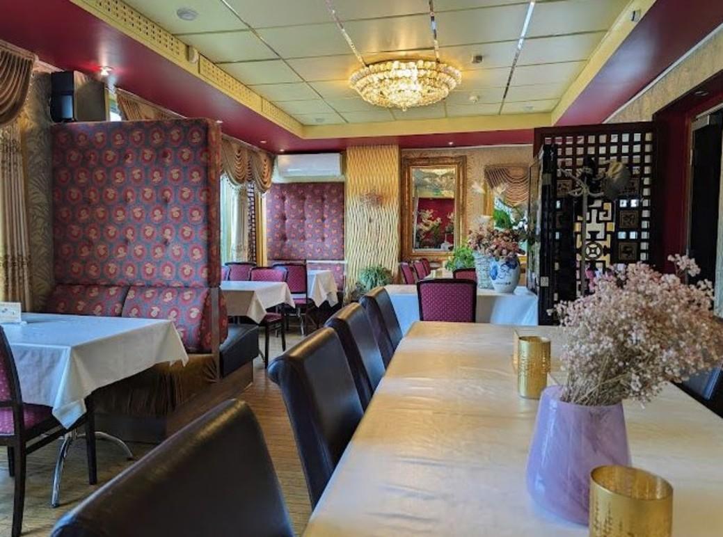 Elegant restaurantinteriør med borddekorasjoner, blomsterarrangementer og en lysekrone i taket.