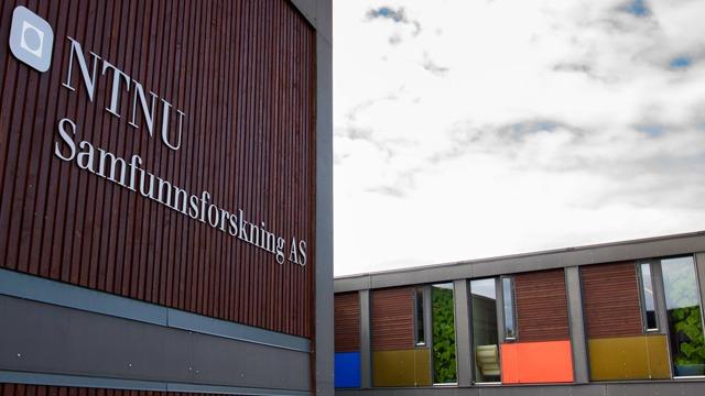 NTNU-bygning med skilt for Samfunnsforståelse AS, moderne arkitektur og fargerike vinduer.