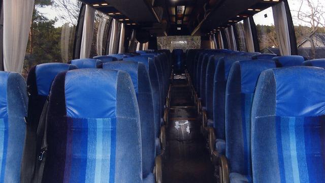 Interiør av en buss med blå seter i rader og tomme midtgang.