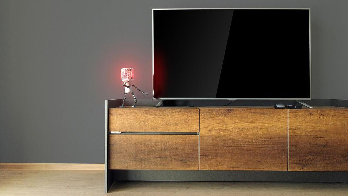 Moderne stue med en stor TV på en trekommode og en rød lampe ved siden av.